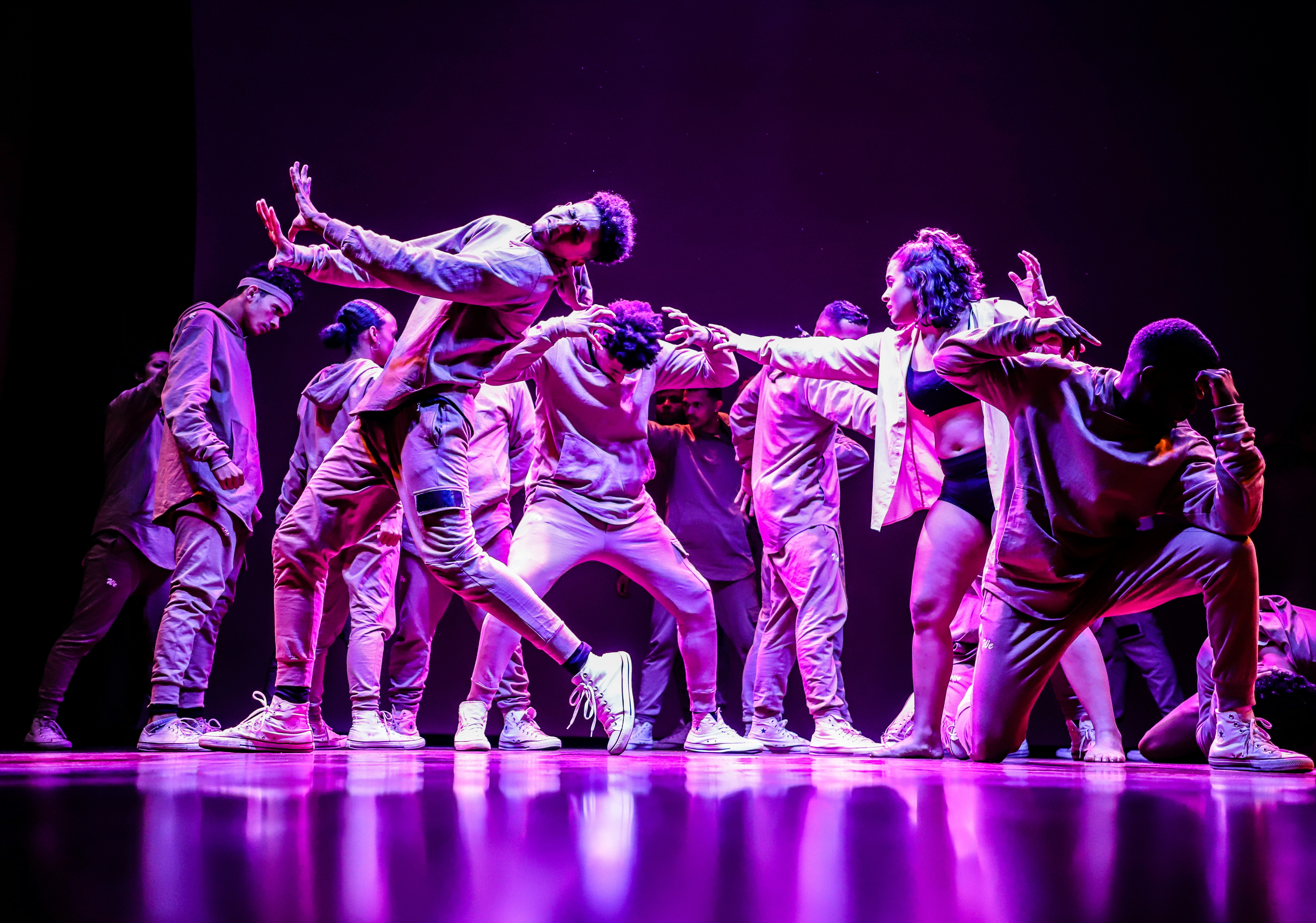 A group of young dancers on stage bathed in purple light.