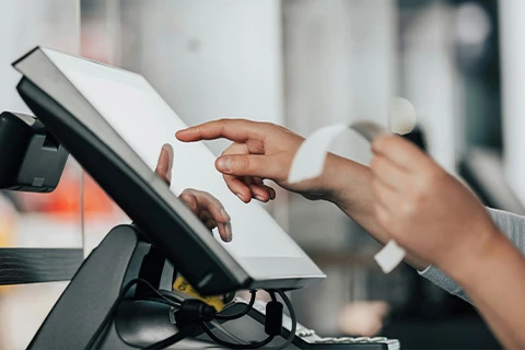 Someone inspecting a receipt whilst using a touchscreen display.