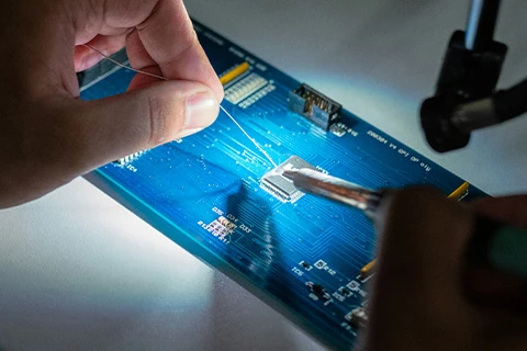 A person solders a chip onto a circuit board.