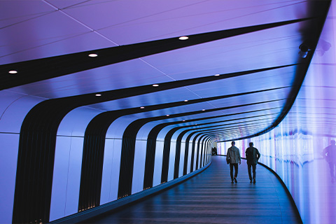 Two people in a neon coloured, futuristic walkway.