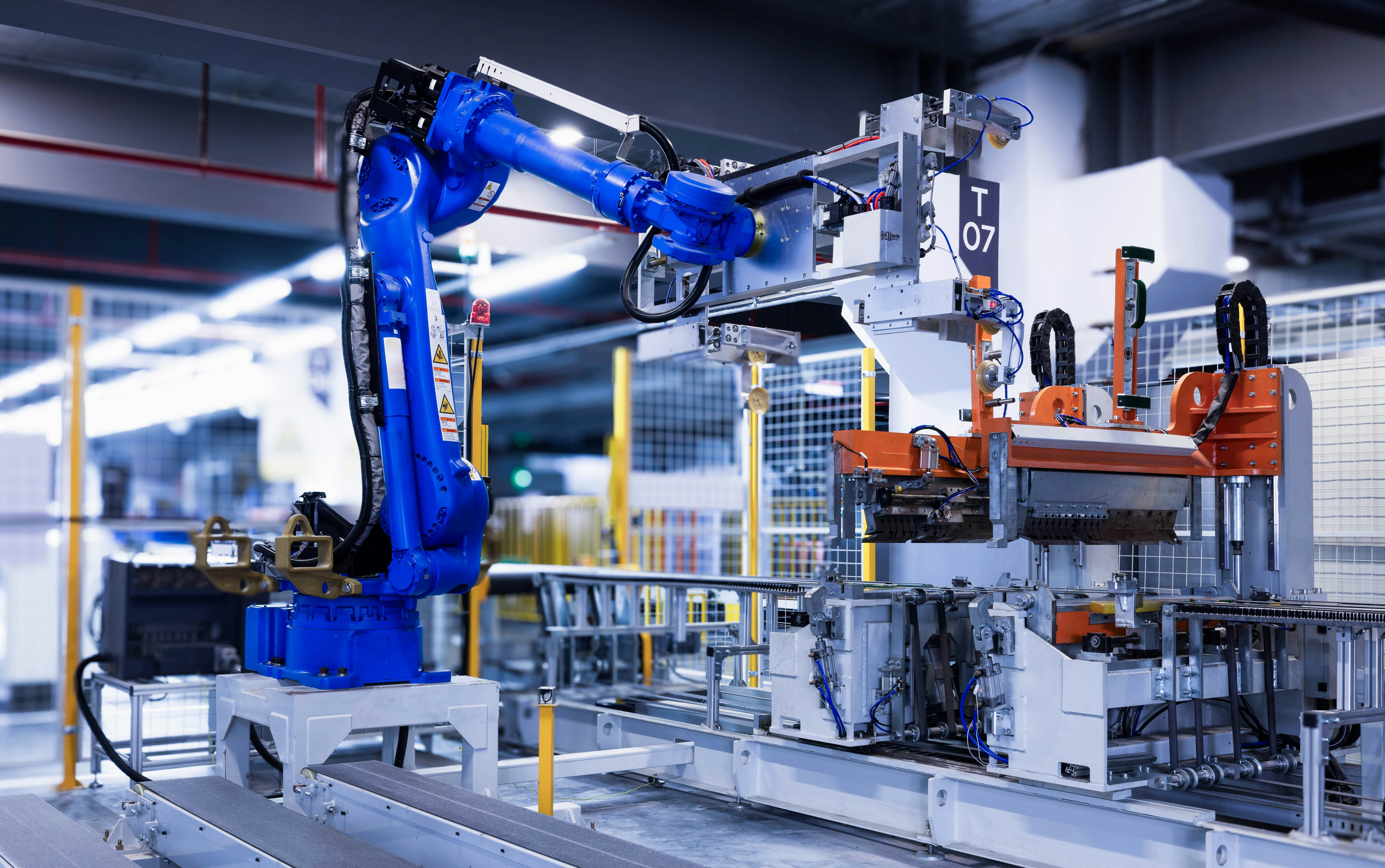 A robot arm is used to construct machinery on a factory floor.